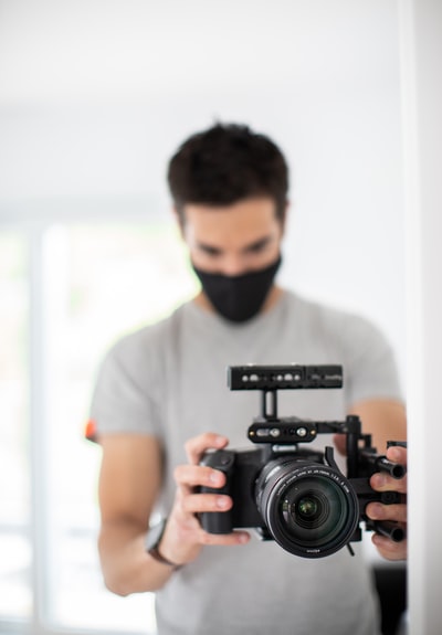 身穿白色圆领t恤,手持黑色单反相机